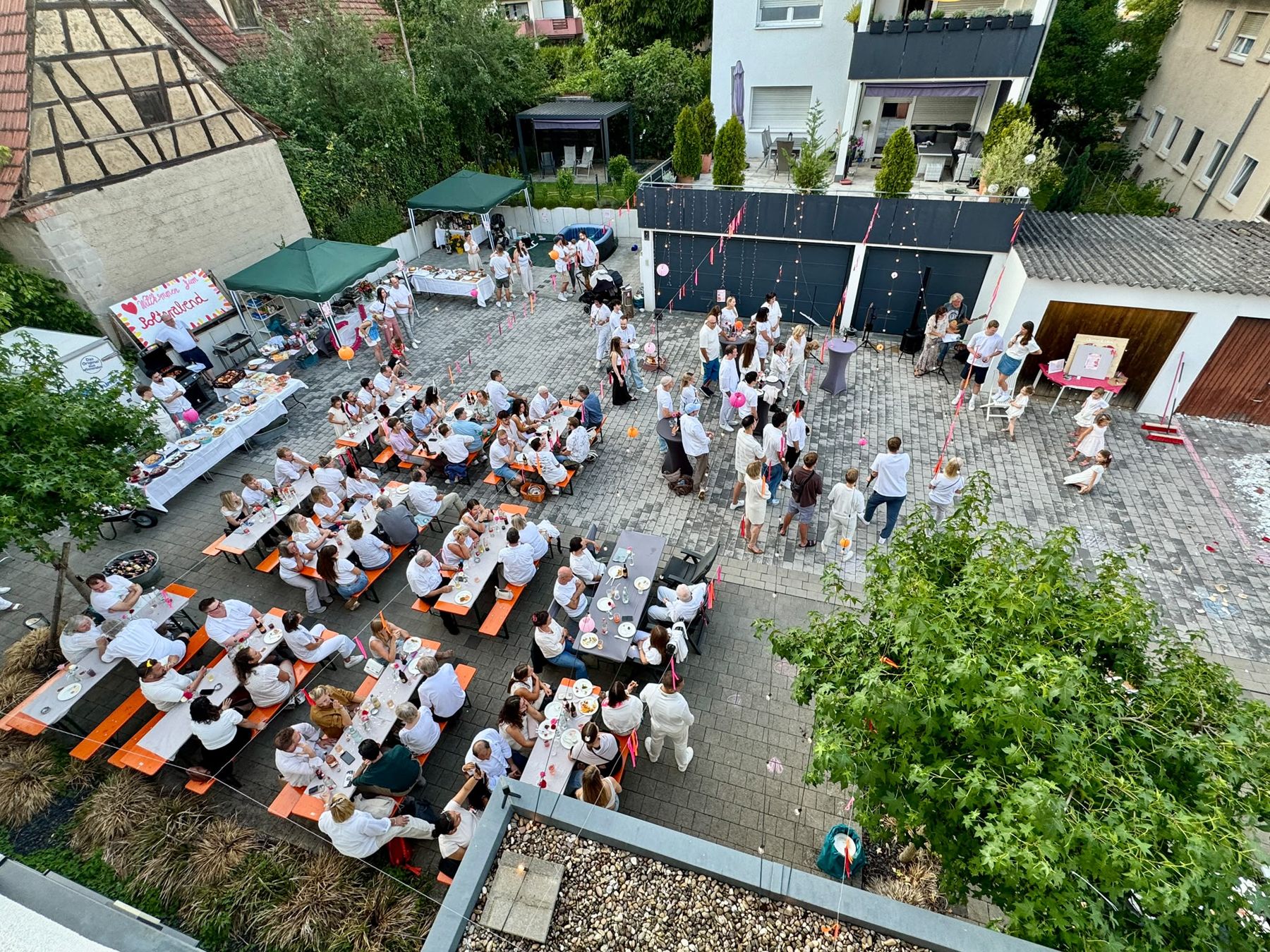 Das ganze Fest von oben: Tafeln, Gäste in Weiß, Band und Tanzfläche